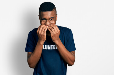 Young african american man wearing volunteer t shirt laughing and embarrassed giggle covering mouth...