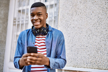 Young african american man smiling happy using smartphone at the city.