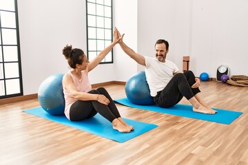 Obraz premium Mature hispanic couple doing excersice and stretching at yoga room. Two adult people doing pilates and flexibility workout