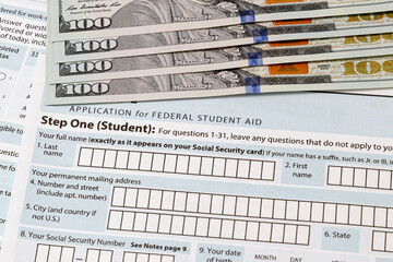 Student loan application and one-hundred dollar bills. Concept of college tuition loan, debt and...