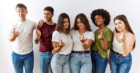 Group of young friends standing together over isolated background beckoning come here gesture with hand inviting welcoming happy and smiling - obrazy, fototapety, plakaty