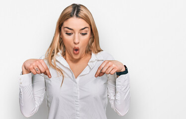 Young caucasian woman wearing casual clothes pointing down with fingers showing advertisement, surprised face and open mouth