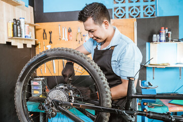 a bicycle mechanic in apron applies bicycle brakes when repairing bicycles in a workshop