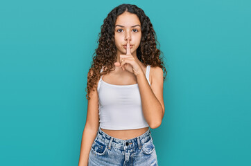 Teenager hispanic girl wearing casual clothes asking to be quiet with finger on lips. silence and secret concept.
