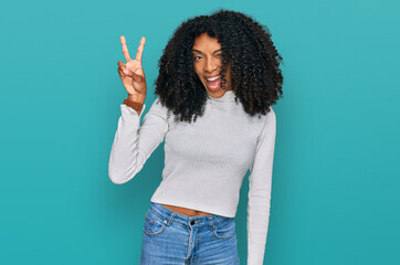 Young african american girl wearing casual clothes smiling with happy face winking at the camera...