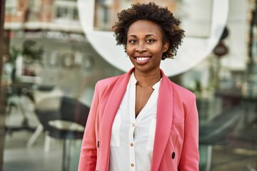 Beautiful business african american woman with afro hair smiling happy and confident outdoors at the city