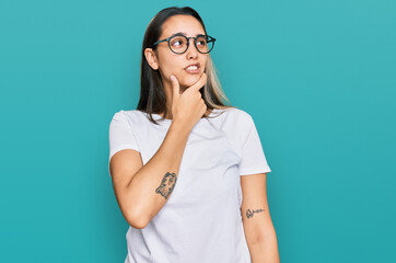 Young hispanic woman wearing casual white t shirt thinking worried about a question, concerned and nervous with hand on chin
