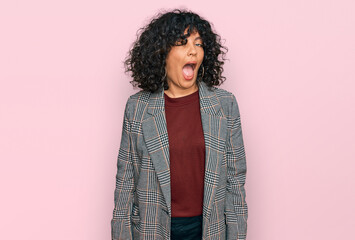 Young hispanic woman wearing business clothes winking looking at the camera with sexy expression,...