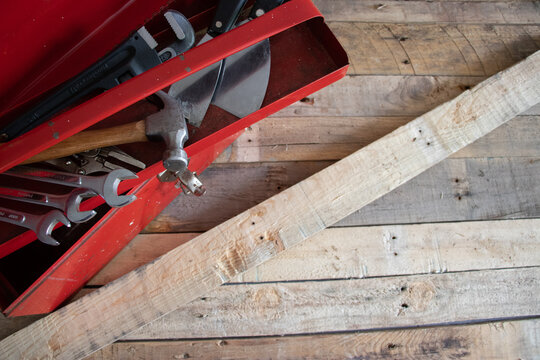 Old red retro handyman toolbox on wooden background.