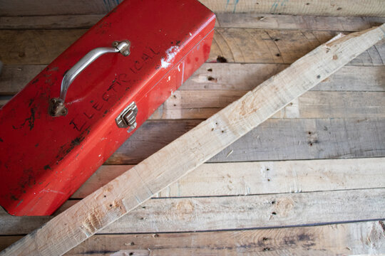 Old red retro handyman toolbox on wooden background.