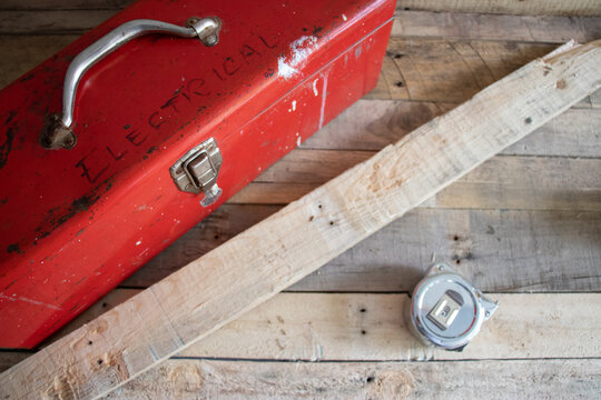 Old red retro handyman toolbox on wooden background.