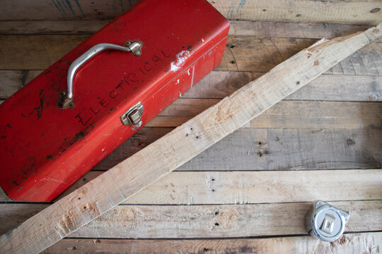 Old red retro handyman toolbox on wooden background.