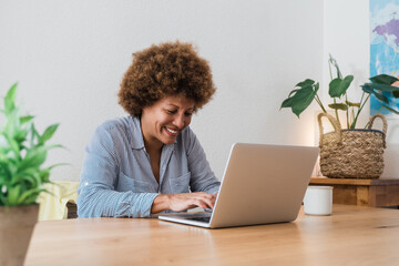 Happy african mature woman using laptop computer at home office - Focus in face