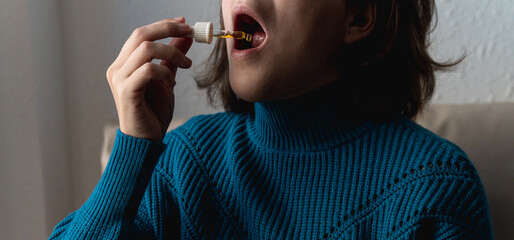 Woman taking cbd oil under tongue - Alternative medicine concept - Focus on dropper © Vane Nunes