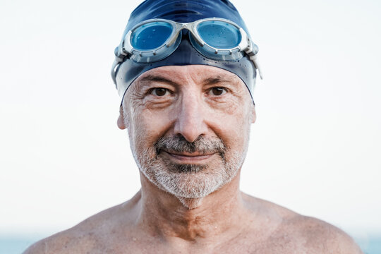 Swimmer senior man looking at camera before training outdoor at the beach - Training, sport water competition concept