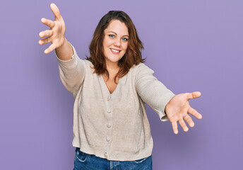 Young plus size woman wearing casual clothes looking at the camera smiling with open arms for hug....