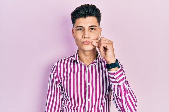 Young hispanic man wearing casual clothes mouth and lips shut as zip with fingers. secret and silent, taboo talking