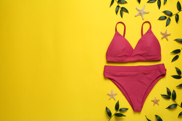 Stylish bikini and beach accessories on yellow background, flat lay. Space for text