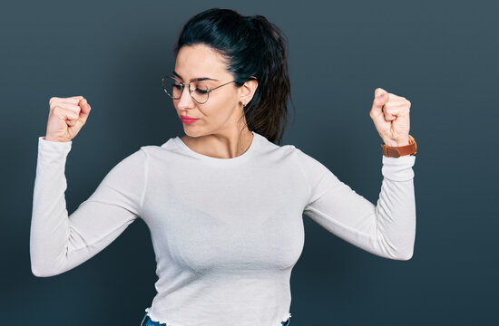 Young hispanic woman wearing casual clothes showing arms muscles smiling proud. fitness concept.