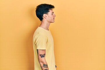 Young hispanic man wearing casual yellow t shirt looking to side, relax profile pose with natural face and confident smile.