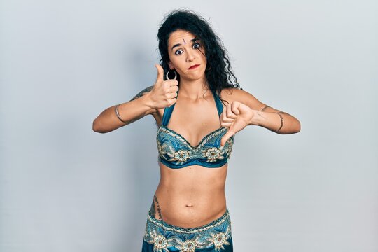 Young Woman Wearing Bindi And Traditional Belly Dance Clothes Doing Thumbs Up And Down, Disagreement And Agreement Expression. Crazy Conflict