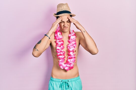 Young hispanic man wearing swimwear and summer hat with hand on head, headache because stress. suffering migraine.