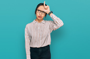 Young hispanic girl wearing casual clothes and glasses making fun of people with fingers on...