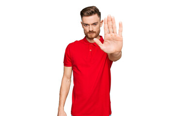 Young redhead man wearing casual clothes doing stop sing with palm of the hand. warning expression with negative and serious gesture on the face.