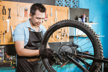 a bicycle mechanic in apron holds the rear mech while fixing problems on bicycles in the workshop