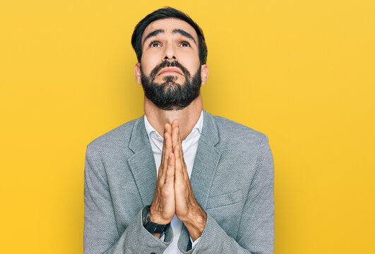 Young hispanic man wearing business clothes begging and praying with hands together with hope expression on face very emotional and worried. begging.