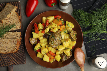 Tasty cooked dish with potatoes in earthenware served on grey table, flat lay
