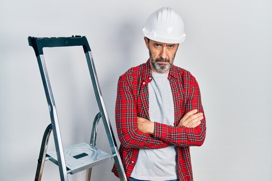 Middle age hispanic worker man with arms crossed gesture using ladder depressed and worry for distress, crying angry and afraid. sad expression.