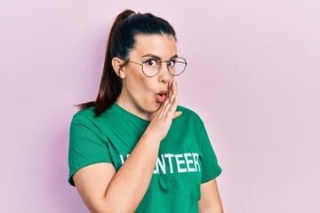 Young hispanic woman wearing volunteer t shirt hand on mouth telling secret rumor, whispering malicious talk conversation