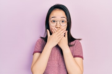 Young chinese girl wearing casual clothes and glasses shocked covering mouth with hands for...
