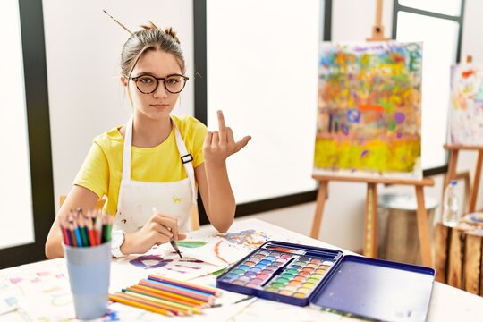 Young Brunette Teenager At Art Studio Showing Middle Finger, Impolite And Rude Fuck Off Expression