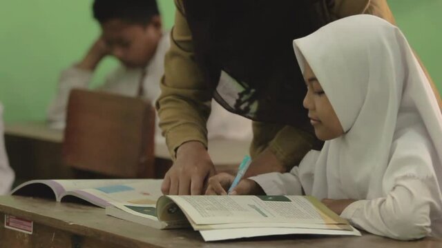 Indonesian muslim teachers who are helping their students in the class