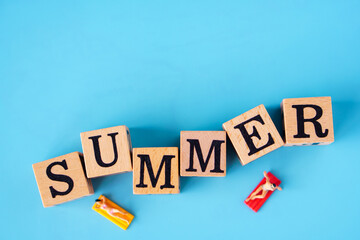 Obraz premium Summer concept : Minature people are taking sun bath on the SUMMER Word written on wooden cubes and a blue background.
