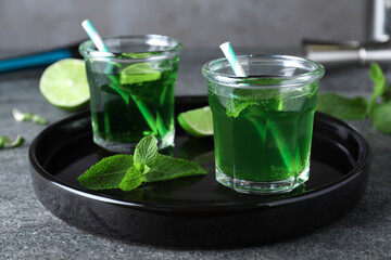 Delicious mint liqueur with green leaves and lime on grey table