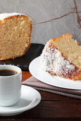 Piece of cake covered with coconut and black coffee.