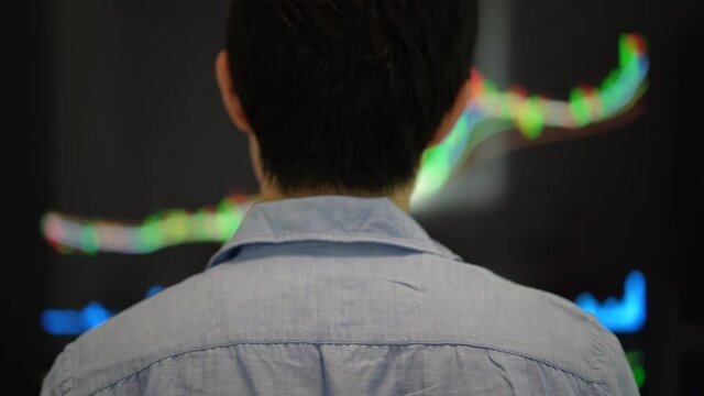 Young money standing in front of screen with stock tickers and graphs changing. Feel exciting for the market. Trading, stock market investment concept b-roll footage. Stock market analyst investment