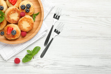 Delicious cottage cheese pancakes with fresh berries and honey on white wooden table, flat lay. Space for text