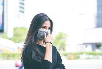Fototapeta premium Face of Asian woman wearing a face mask for protection virus or pollution with outdoor city background. coronavirus protect. Sick and other protect such as Air, Dirt, Fever. Health concept. New Normal