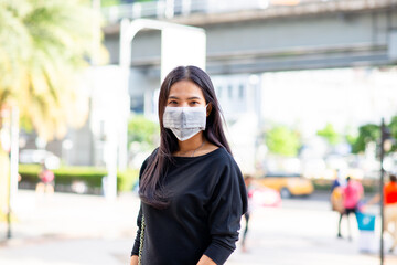 Asian woman be wearing a face mask for protection virus or pollution Hand holding a mask on outdoor city background. coronavirus protect. Sick protect such as Air, Dirt, Fever. Health.