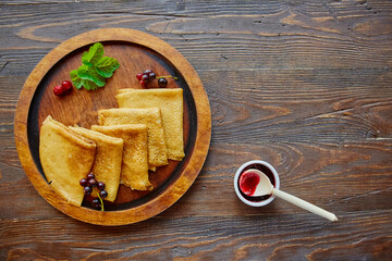 Crepes on a plate on a wooden background. Thin pancakes with crispy crust. Maslenitsa. Pancakes for breakfast and carnival. Food background.