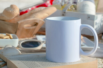 Fototapeta na wymiar close up image of picnic, mug of coffee, sunglasses bread and book on a tropical beach