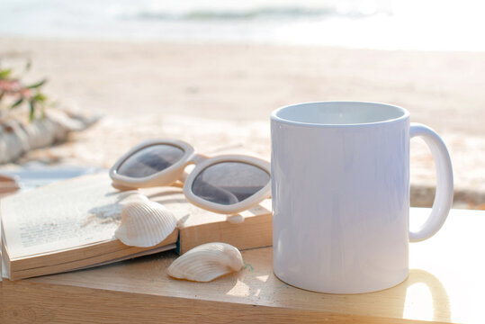Image of beach picnic, mug of coffee, sunglasses and book on a tropical beach
