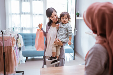 Fototapeta premium mother and kid shopping in the mall buying some clothes