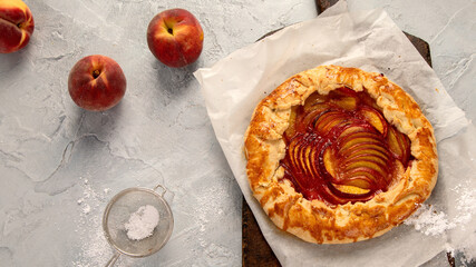 Peach gallete on baking paper on wooden background. Freshly prepared homemade pie.