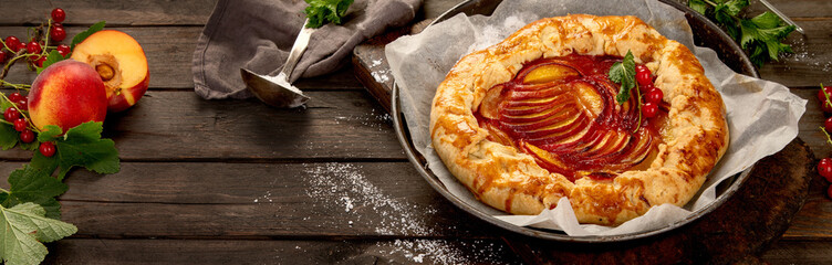 Peach gallete on baking paper on wooden background. Freshly prepared homemade pie.