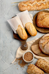Naklejka premium Various types of fresh baked bread on light gray background.